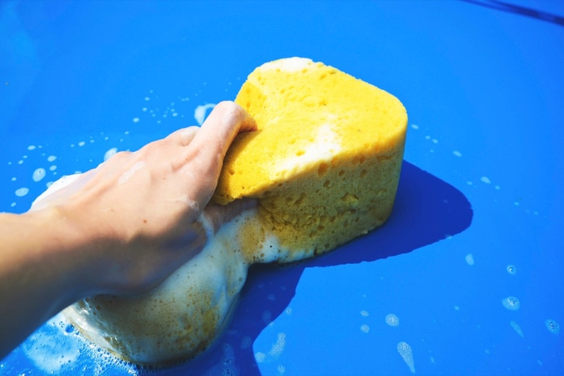 Hand washing a car with a sponge and fresh suds